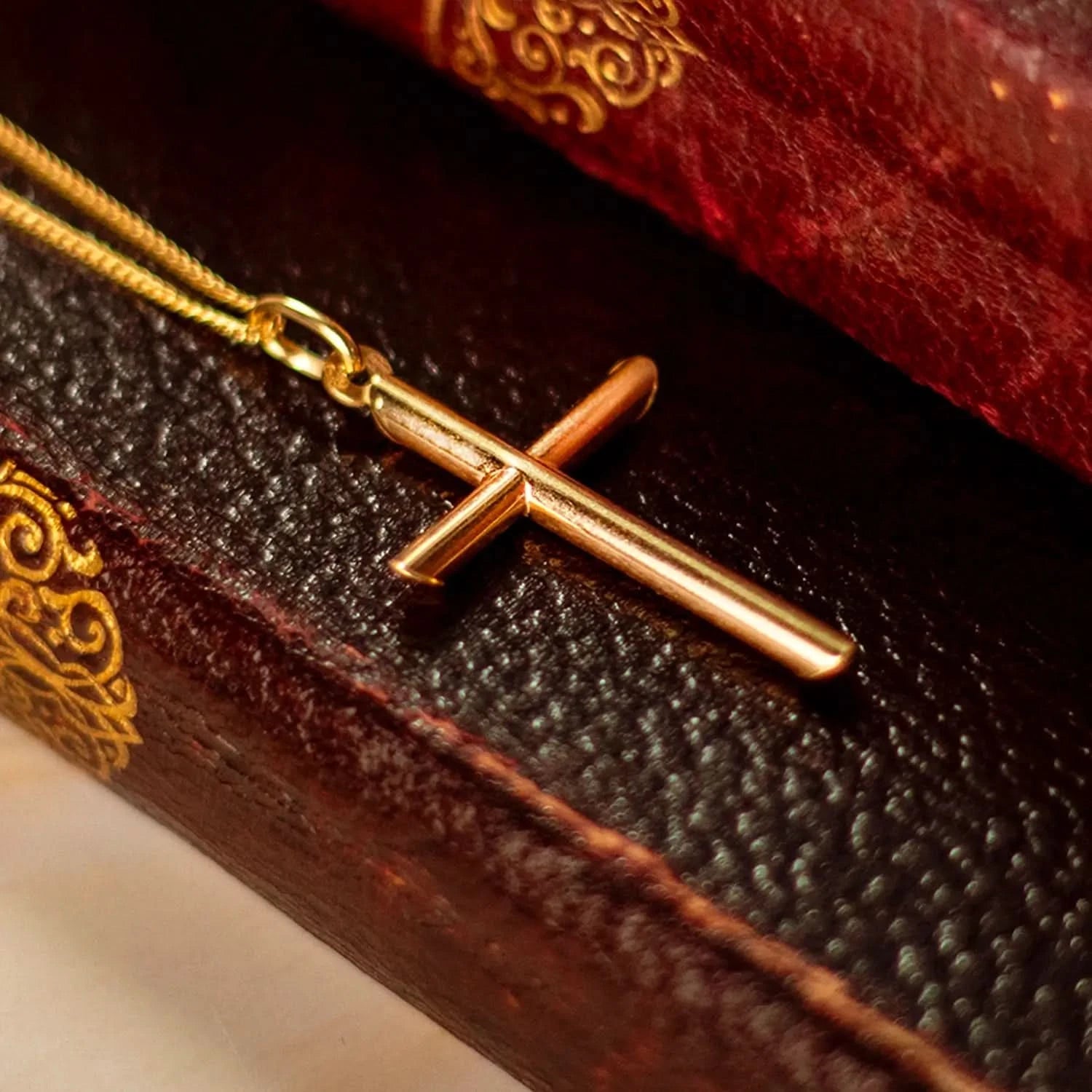 gold cross necklace, sturdy gold curb chain, high polish finish, rounded edges, religious Christian pendant for men and women, sitting on leather books, bible