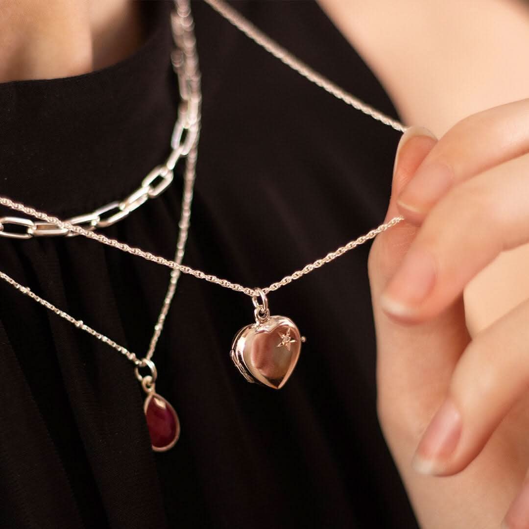 Model in black top wearing a 2 photo diamond heart locket in silver on a rope chan 