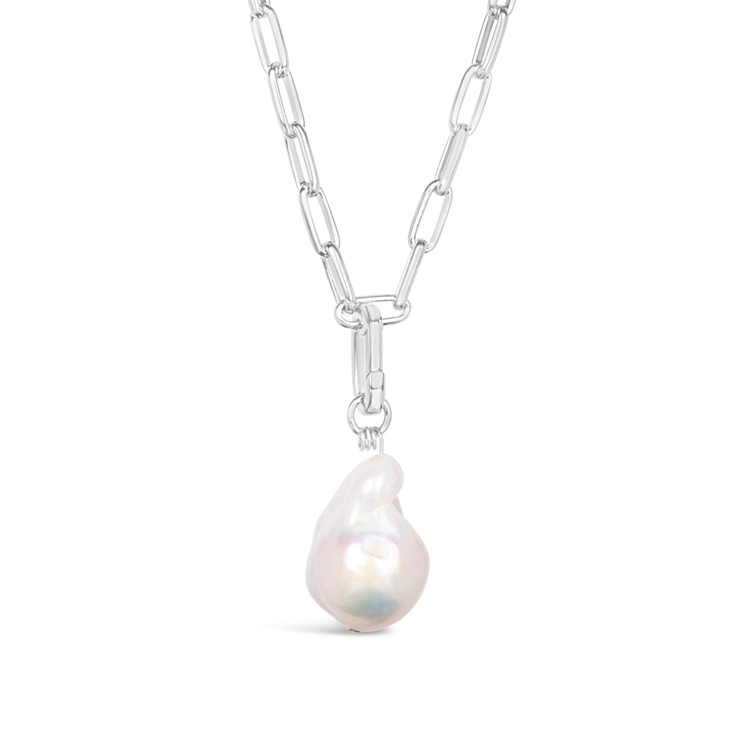 close up of white baroque pearl on silver paperclip chain on white background
