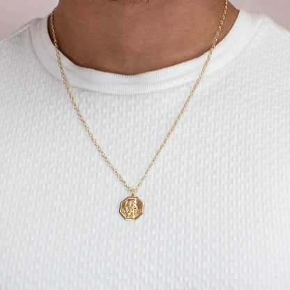 Gold st Christopher necklace with a hexagonal pendant on a white shirt