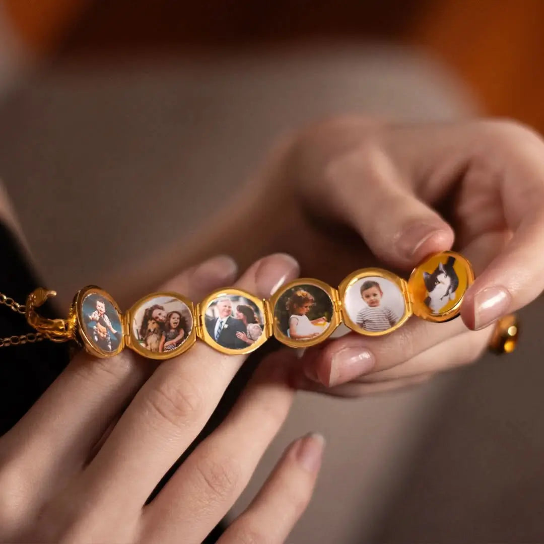 Gold memory keeper locket with circular panels featuring photos held by a person.