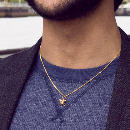 male model wearing a bee necklace in gold