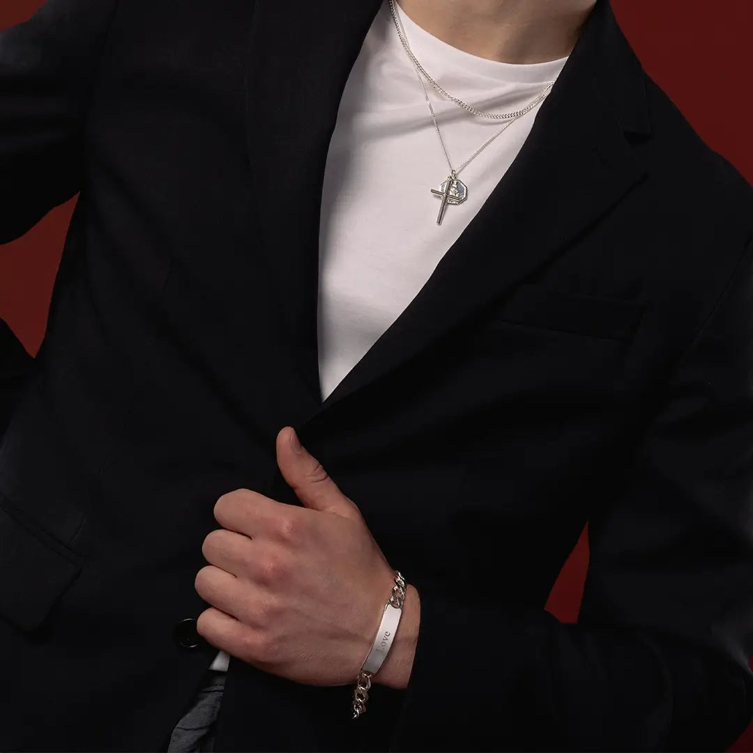 Male model wearing a medium silver ID bracelet with layered silver cross and St Christopher necklaces