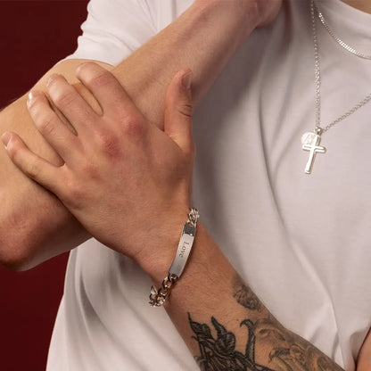 Close-up of male model wearing a medium sterling silver ID bracelet engraved with Love, with layered silver necklaces