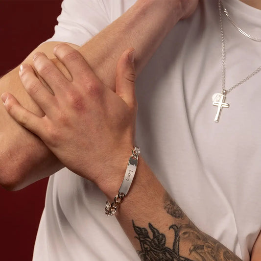 Close-up of male model wearing a medium sterling silver ID bracelet engraved with Love, with layered silver necklaces