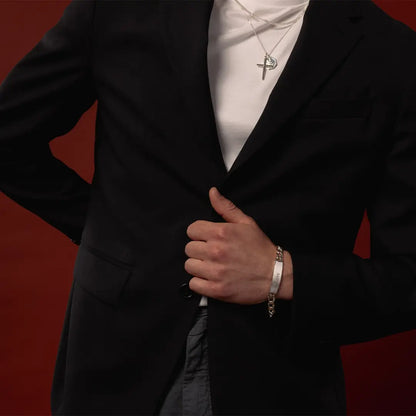 Close-up of male model wearing a medium sterling silver ID bracelet with layered silver cross and St Christopher necklaces