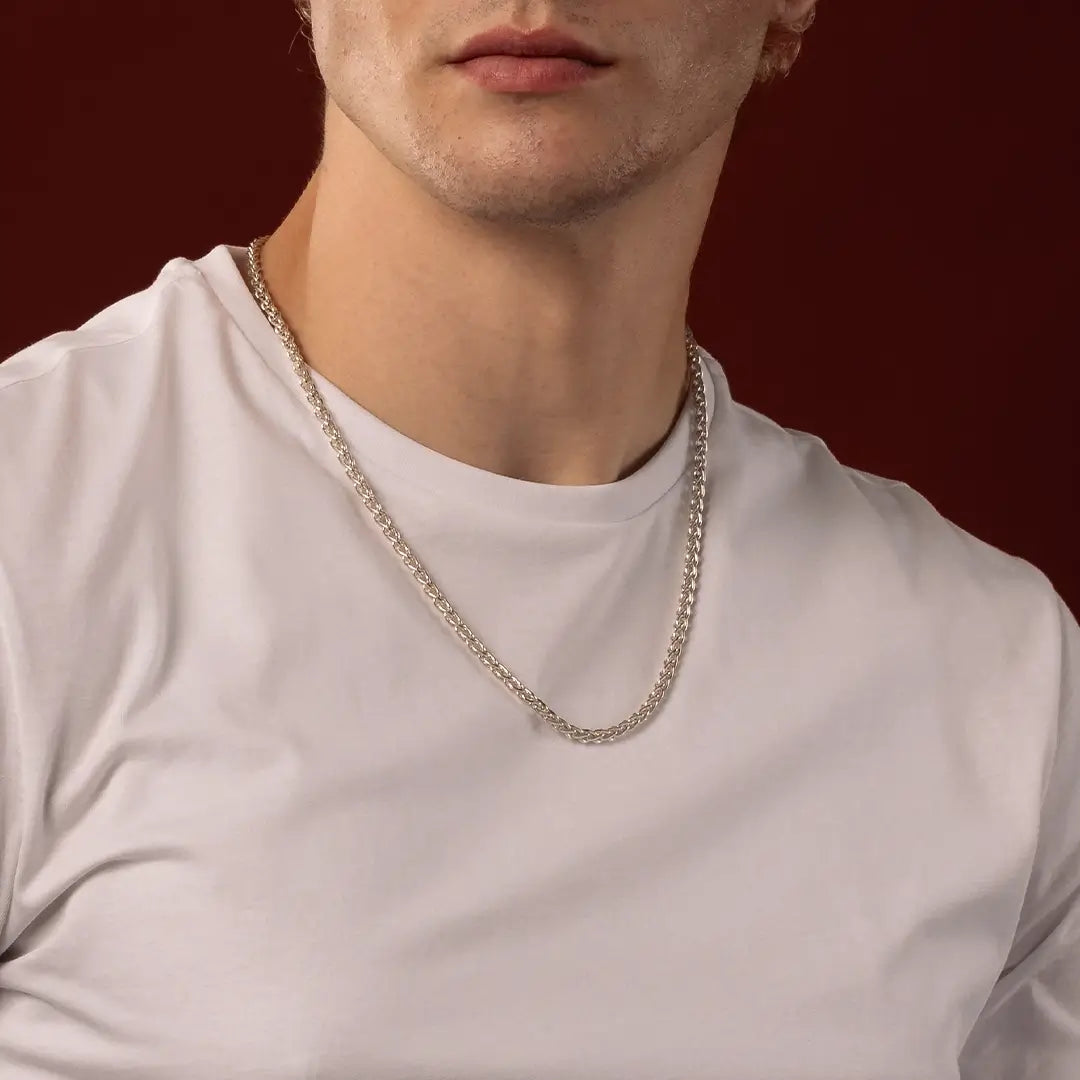 Male model wearing a sterling silver Spiga chain necklace against a dark red background