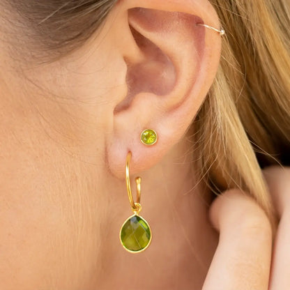 18ct gold vermeil peridot hoop earring and matching peridot stud worn on the ear, featuring faceted green peridot gemstones.