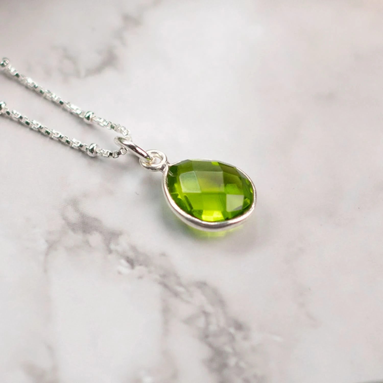 peridot silver necklace charm on white surface