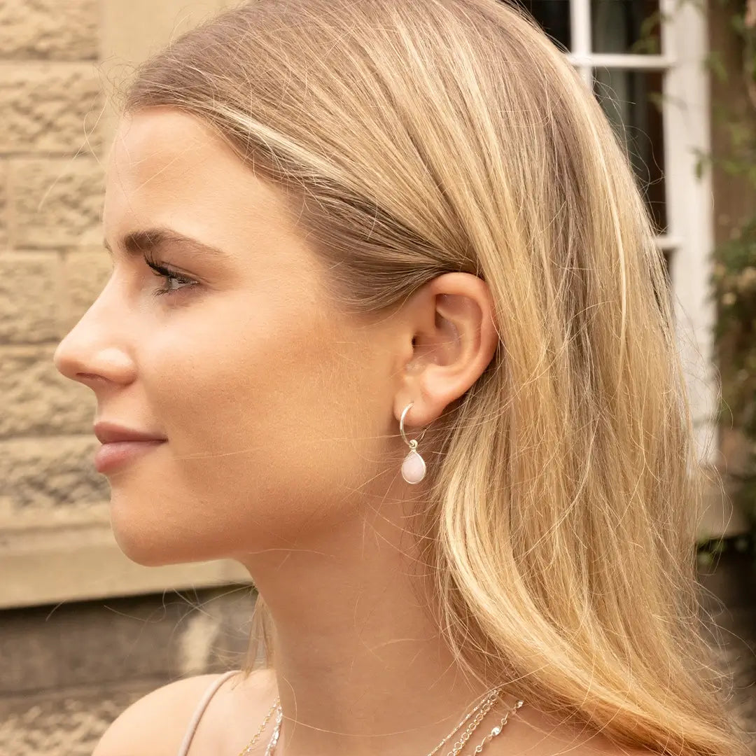 Model wearing sterling silver pink opal drop hoop earrings, showcasing teardrop pink opal gemstones in a refined, minimalist design.