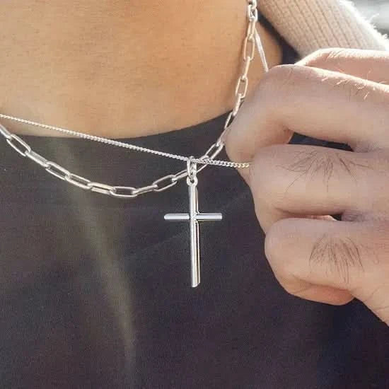 man wearing silver cross necklace, sturdy silver curb chain, high polish finish, rounded edges,  unisex pendant for men and women, paperclip chain, holding chain