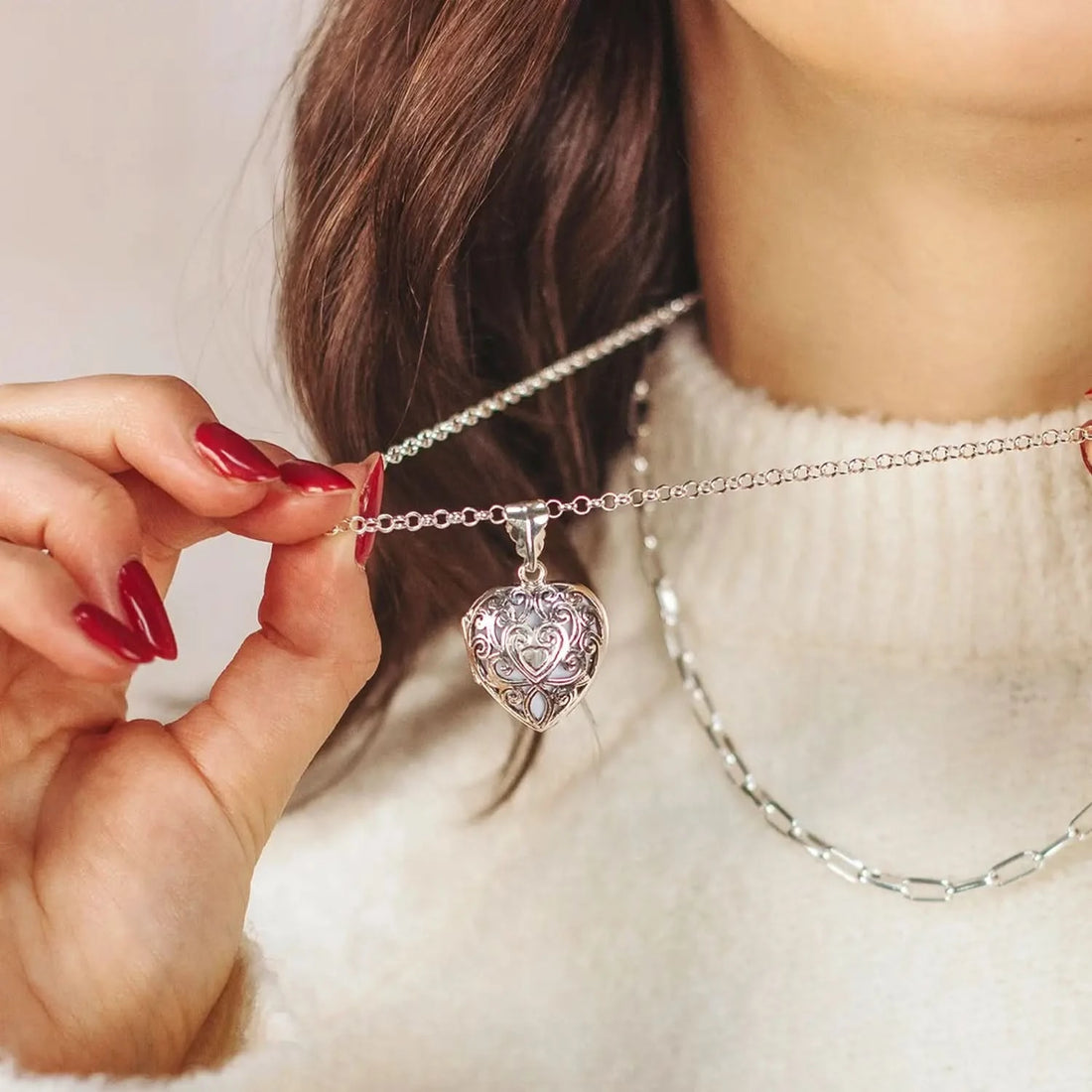 Silver filigree heart locket necklace worn on model with layered chains