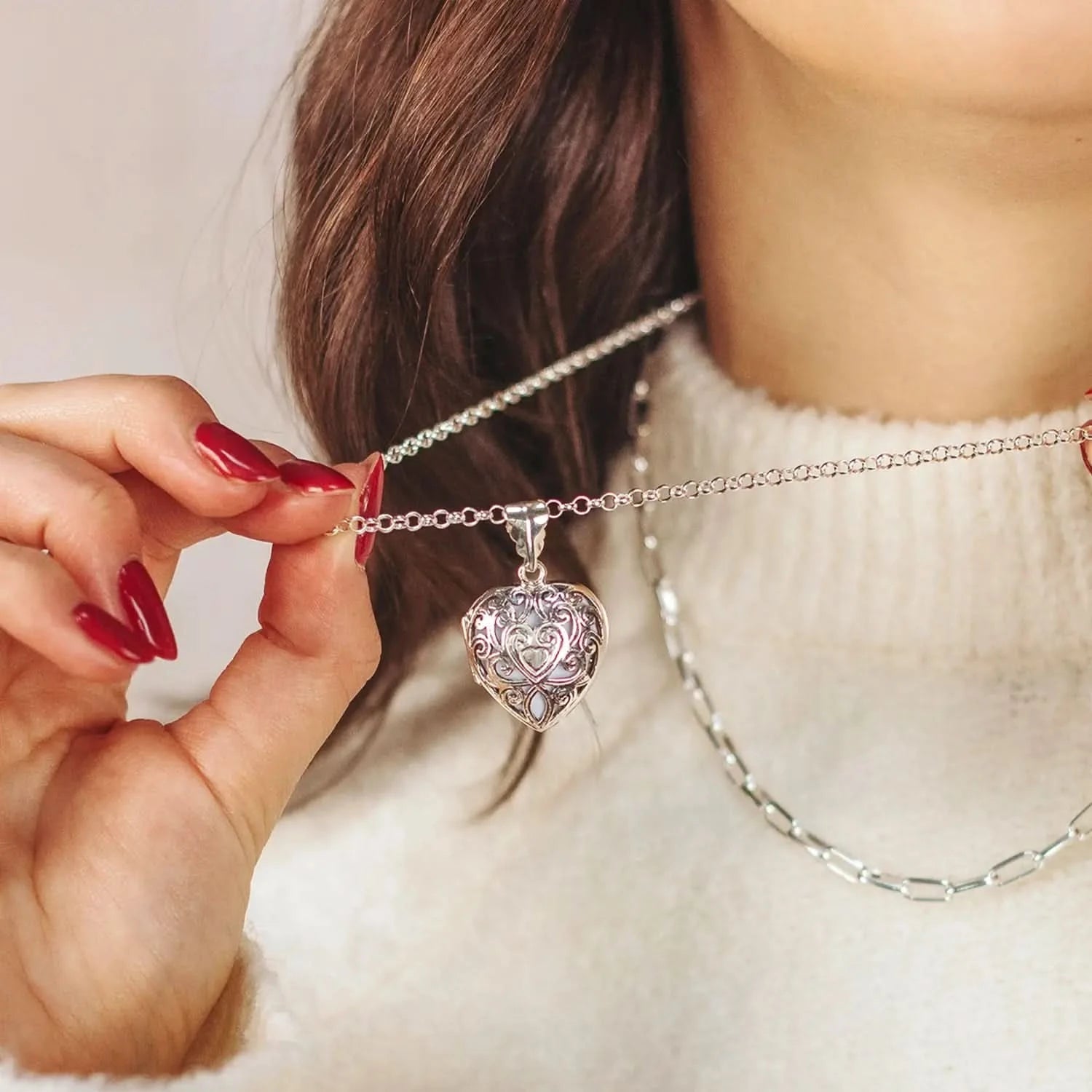 Silver filigree heart locket necklace worn on model with layered chains