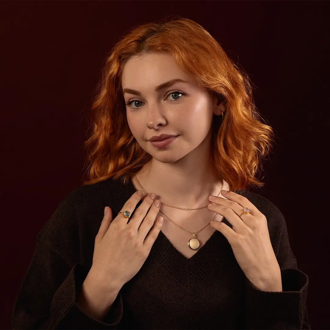 Model wearing a solid 9ct gold round locket necklace with layered gold jewellery