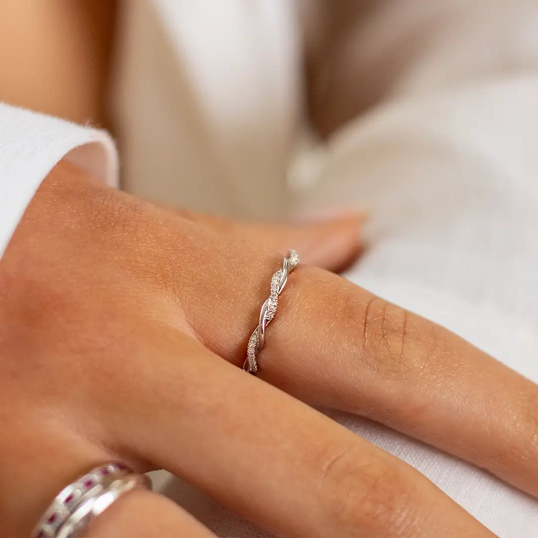 Close-up of a hand wearing a 9ct white gold twisted rope ring featuring alternating polished and pavé diamond-set strands, photographed in soft natural light.