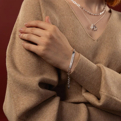 Woman wearing a sterling silver ID bracelet engraved with Forever, close-up