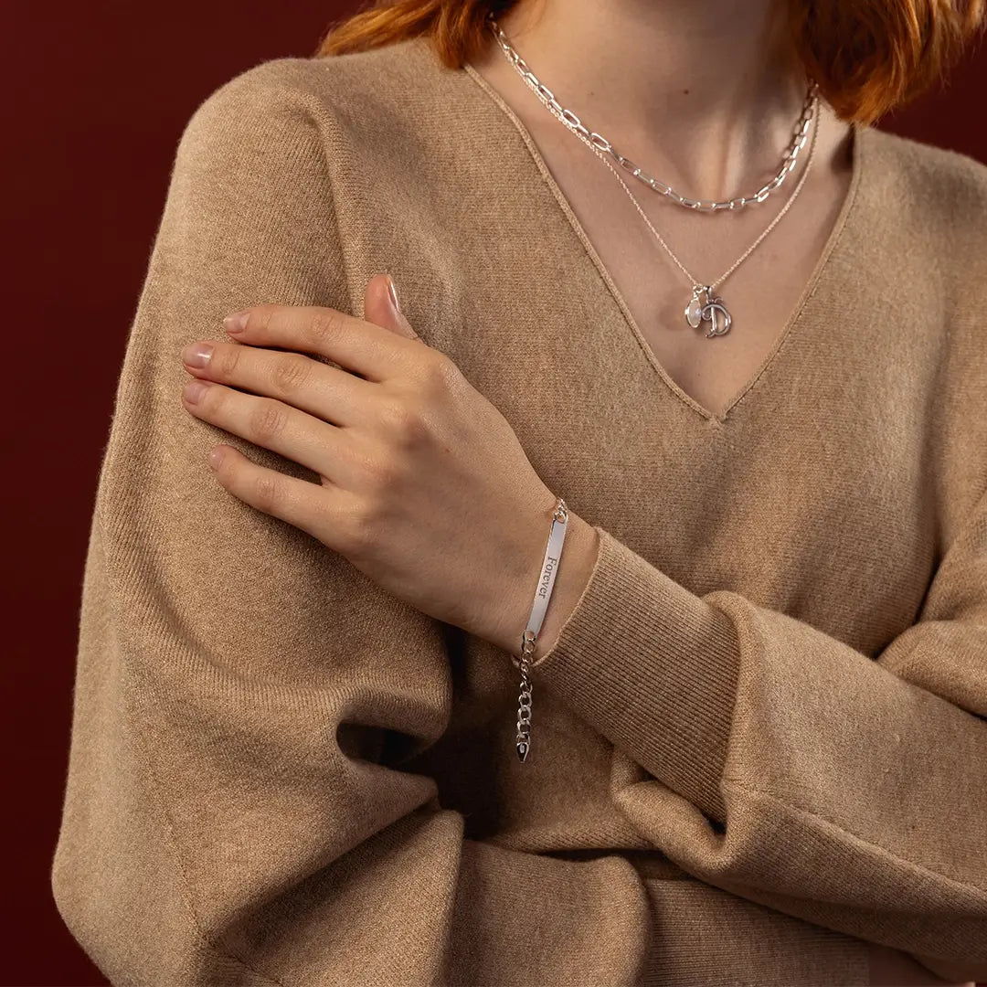 Woman wearing a sterling silver ID bracelet with Forever engraving, wrist close-up