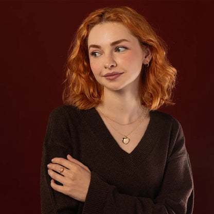 Model wearing a polished solid 9ct gold heart locket necklace layered with gold jewellery