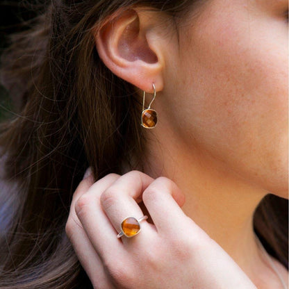close up of model wearing citirne earrings and cocktail ring