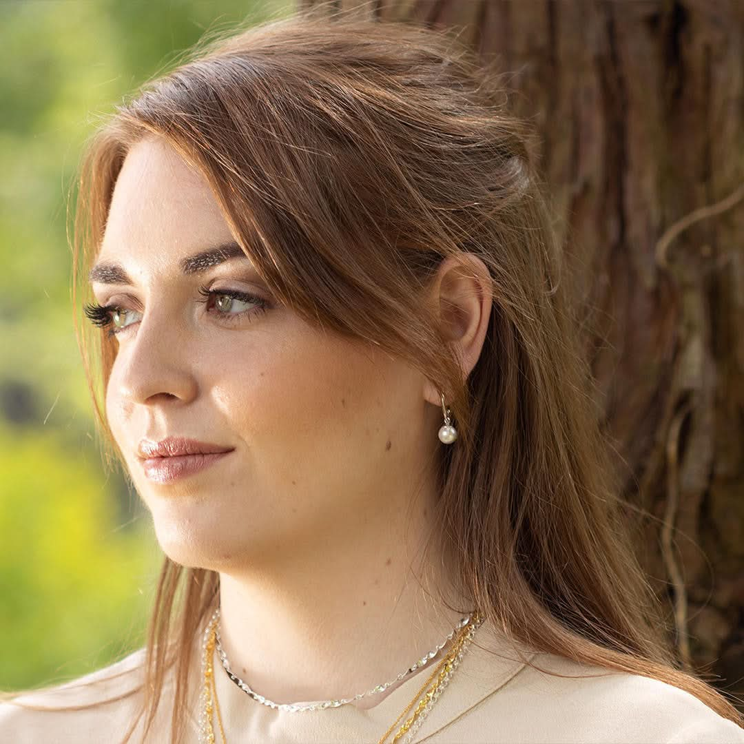 close up of model wearing round pearl drop hoop earrings in ivory silver