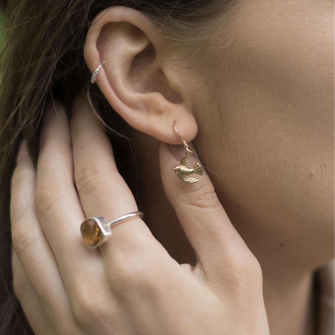 close up of model wearing gold bird earrings