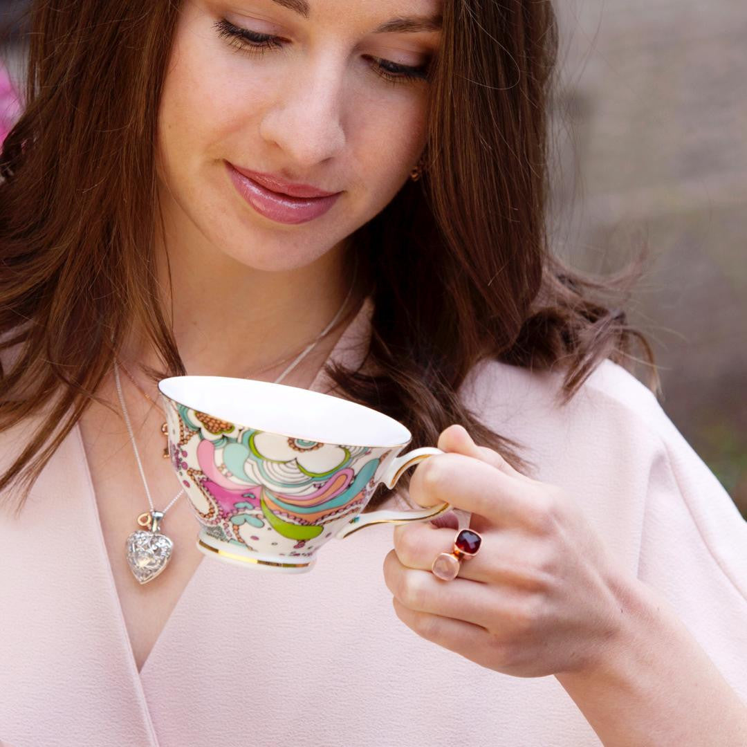 model wearing two rose gold cocktail rings whilst holding tea cup 