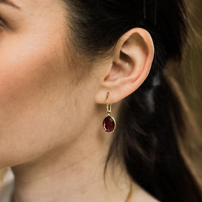 model wearing garnet drop hoop earrings in gold