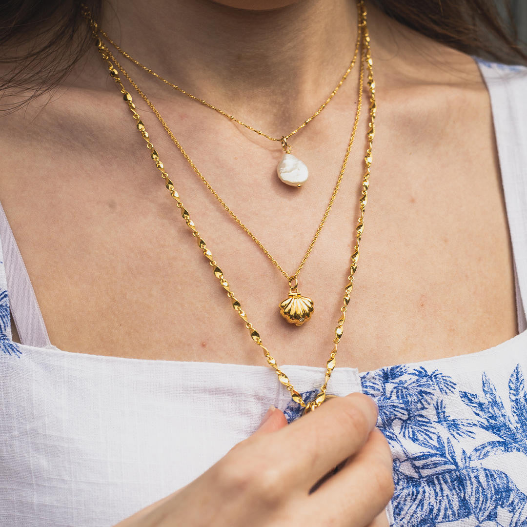 gold shell charm necklace worn by a model