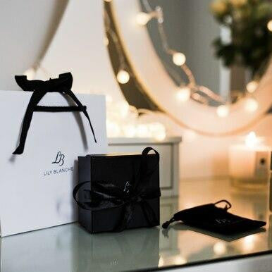 lily Blanche gift packaging with white gift bag, black ribbon-tied box and velvet jewellery storage pouch.