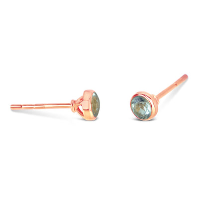 Blue topaz mini stud earrings in rose gold facing the side on a white background