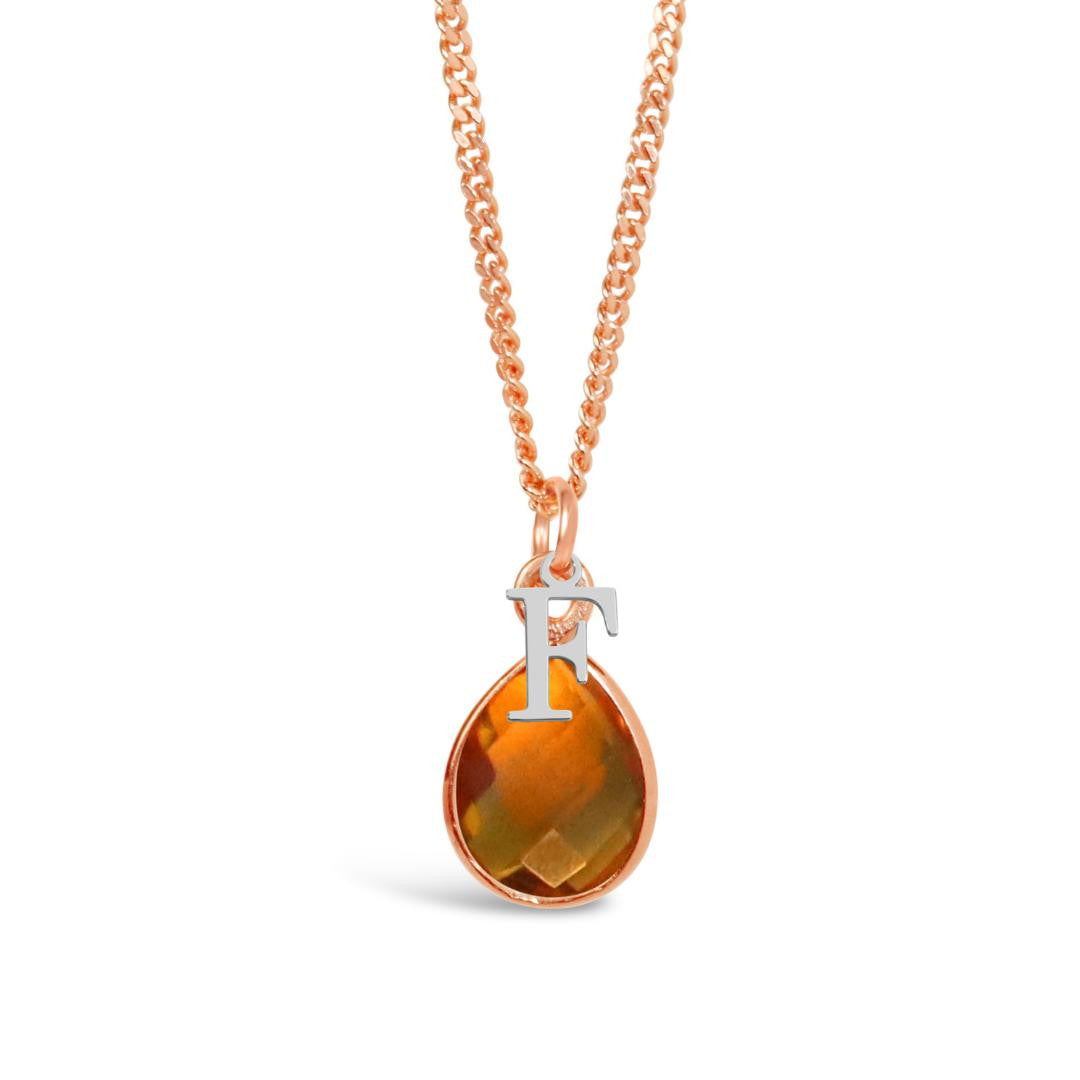 citrine charm necklace in rose gold with silver initial charm on a white background