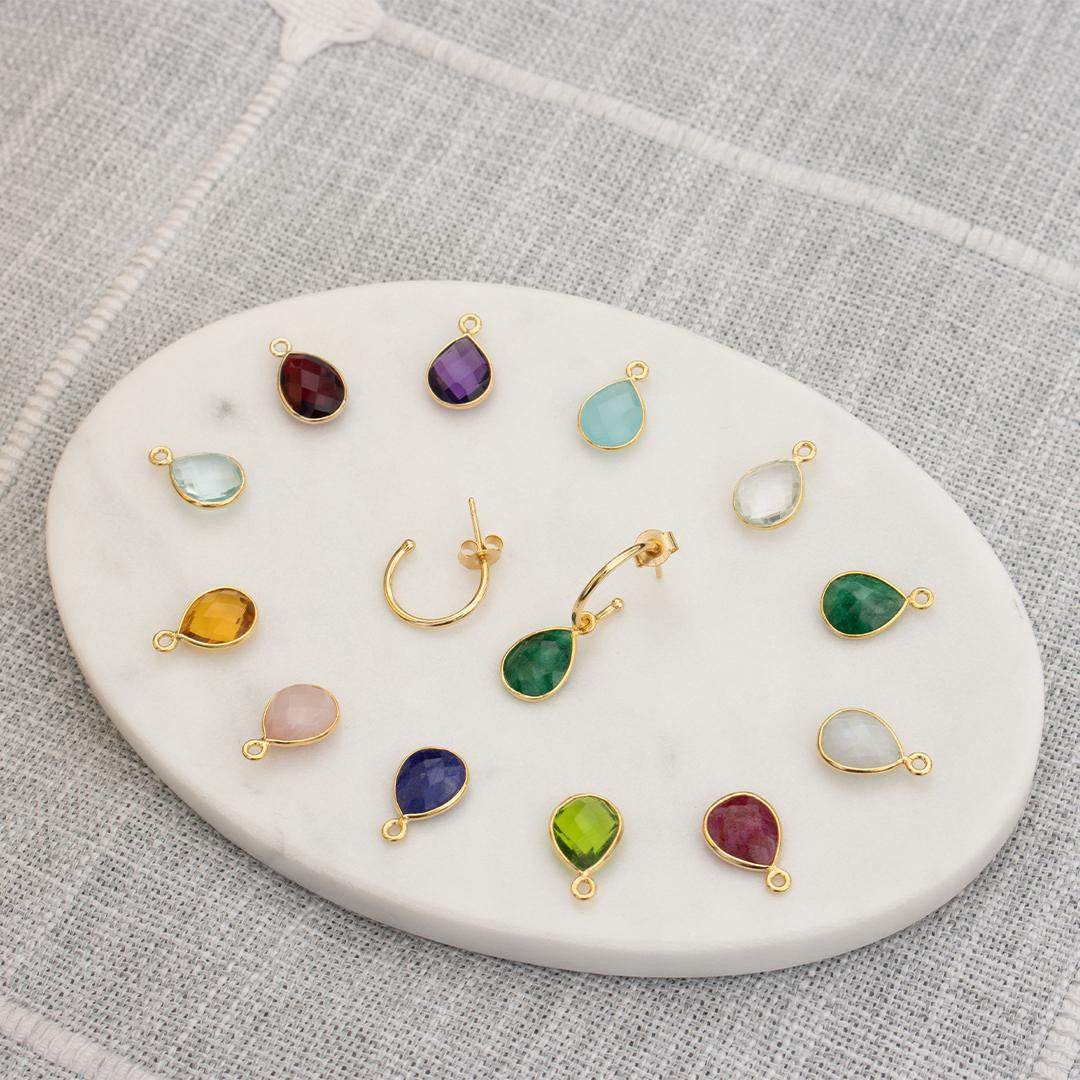 birthstones and drop hoop earrings on a white platter