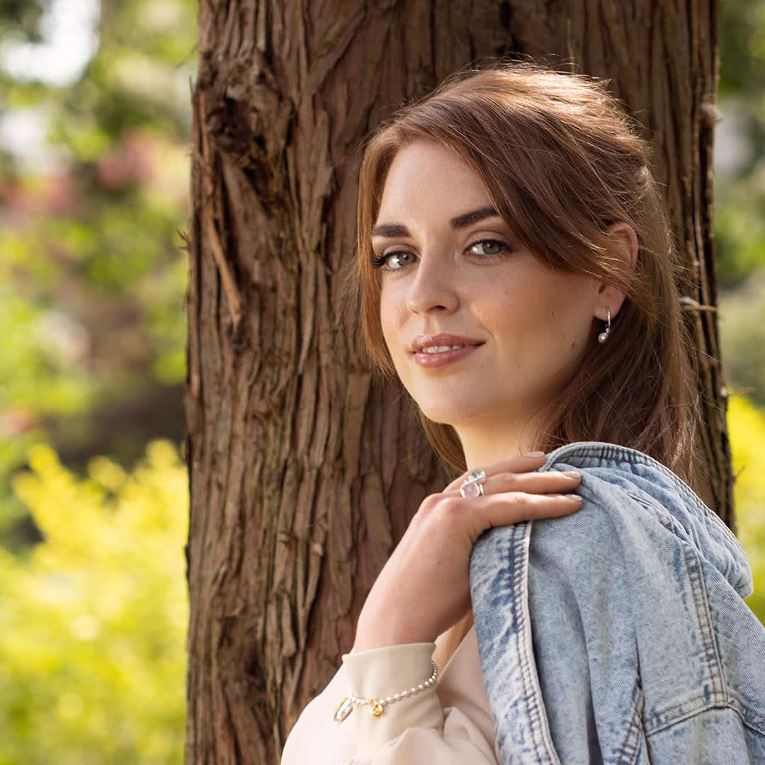 Model wearing sterling silver and gold padlock and key bracelet, holding denim jacket