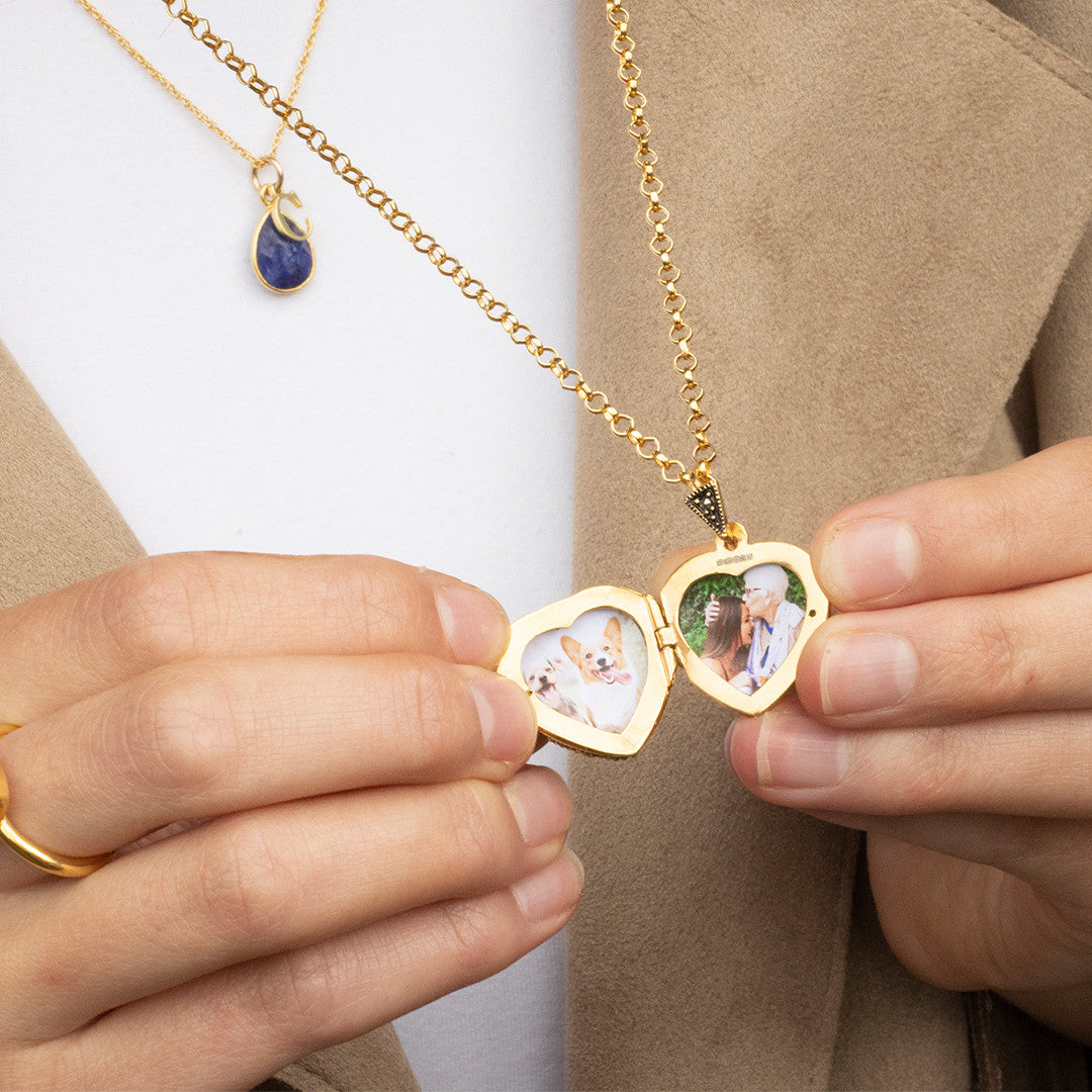 women holding opened sapphire vintage heart locket in gold to reveal photos