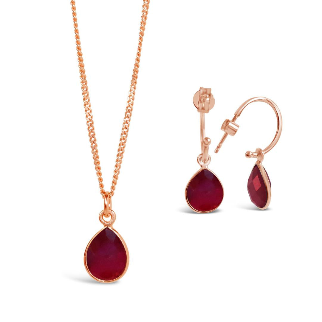 garnet drop hoop earrings and necklace in rose gold on a white background