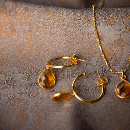 citrine drop hoop earrings in gold sitting on a piece of fabric