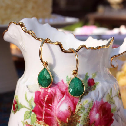 emerald drop hoop earrings in gold hanging out of jug