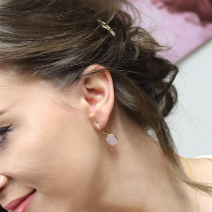 close up of model wearing rose quartz earrings in gold 