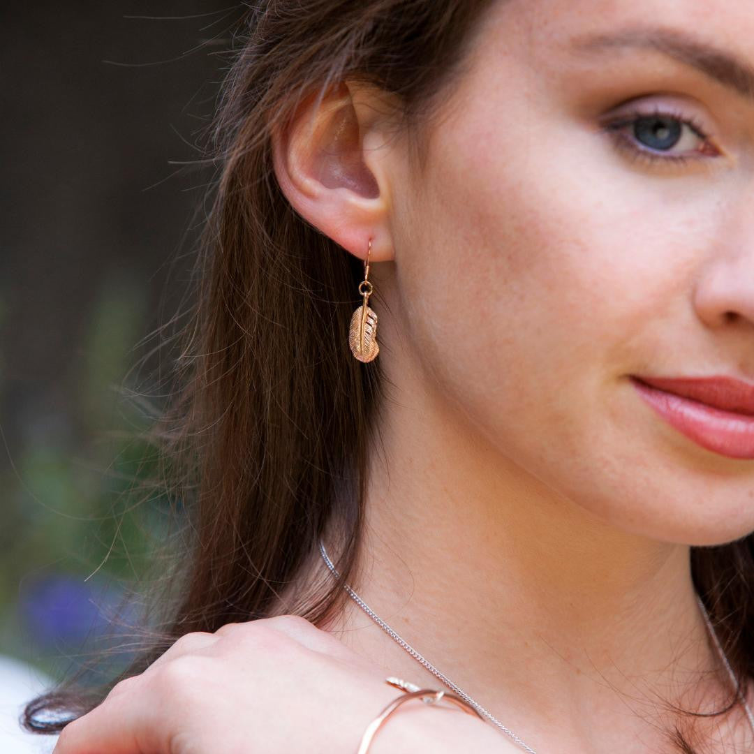 model wearing feather earrings in gold