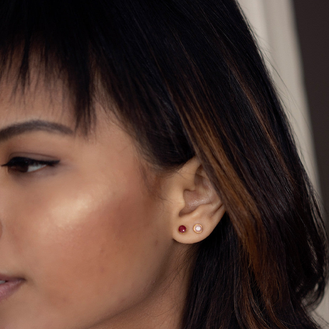 Up close model image wearing pink opal mini stud earrings in gold