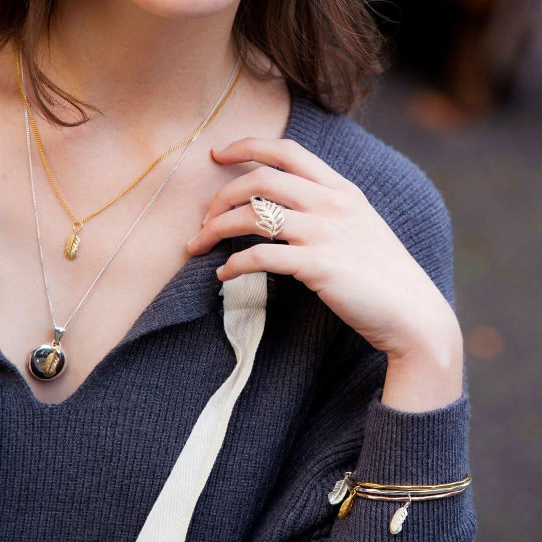 close up of model wearing collection of jewellery with feather charms attached