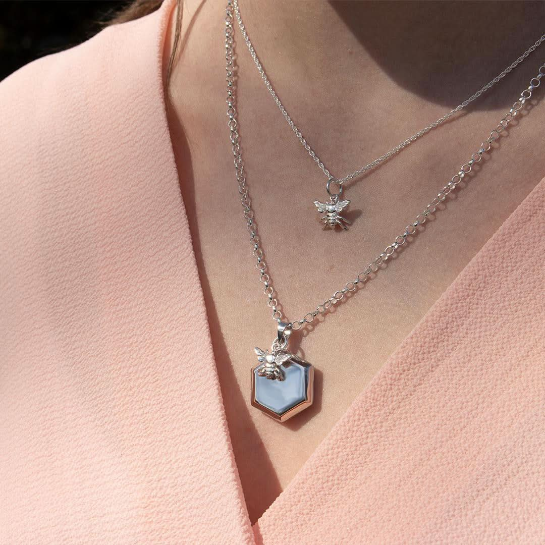 model wearing hexagon locket and bee pendant