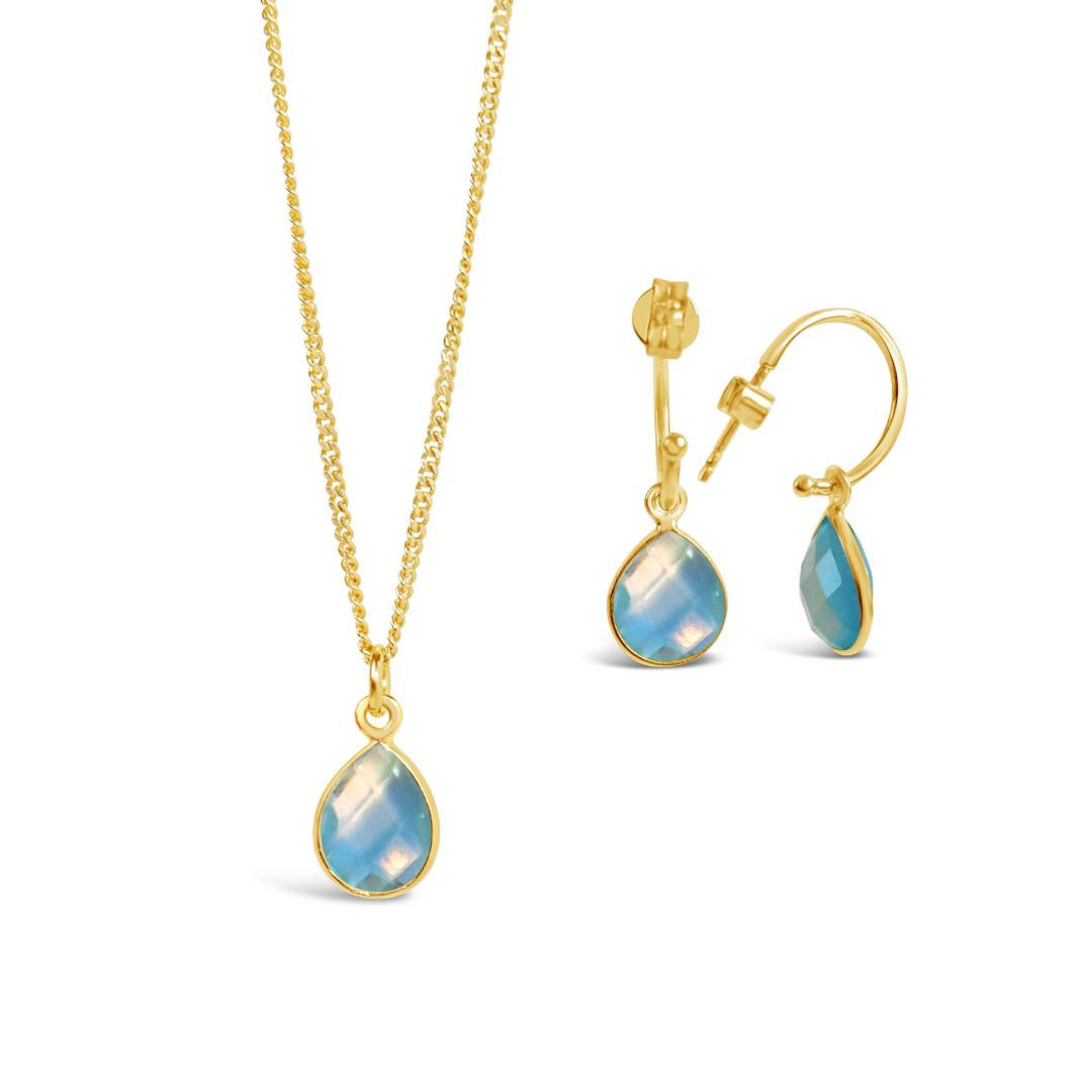 blue topaz charm necklace and drop hoop earrings on a white background