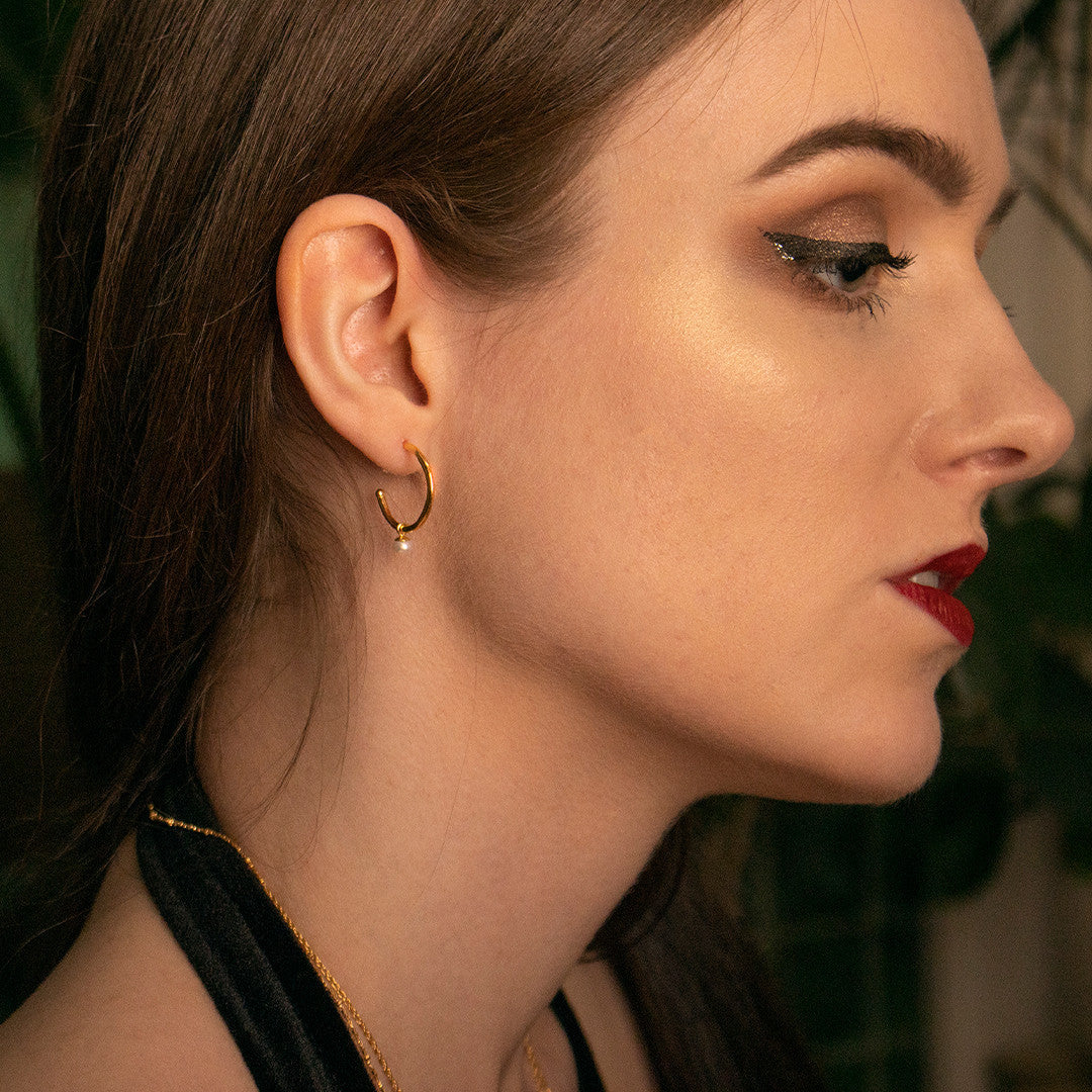 model wearing dainty pearl drop hoop earrings in ivory gold