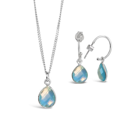 blue topaz necklace and drop hoop earrings in silver on a white background