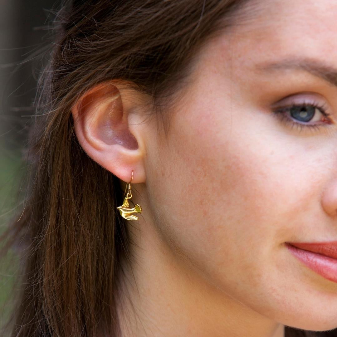 close up of model wearing gold bird earrings