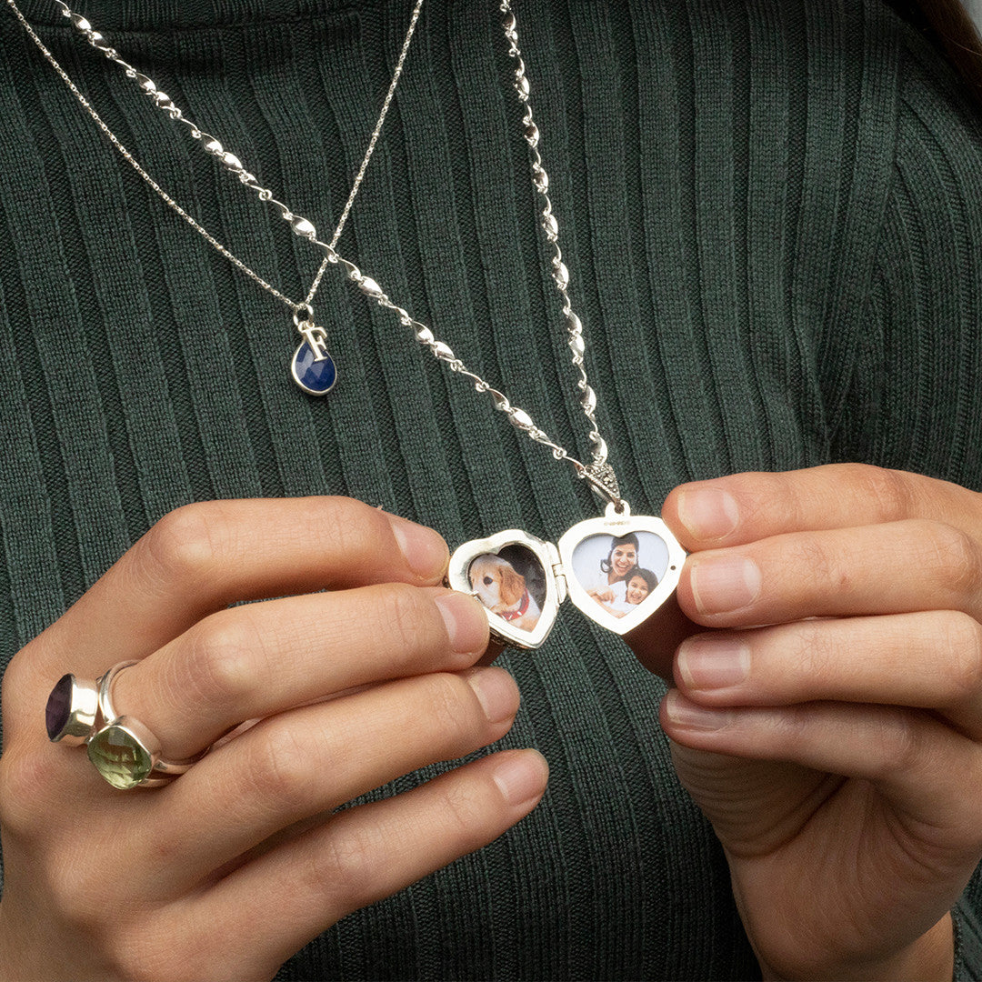 women holding sapphire vintage heart locket in white gold to reveal photos