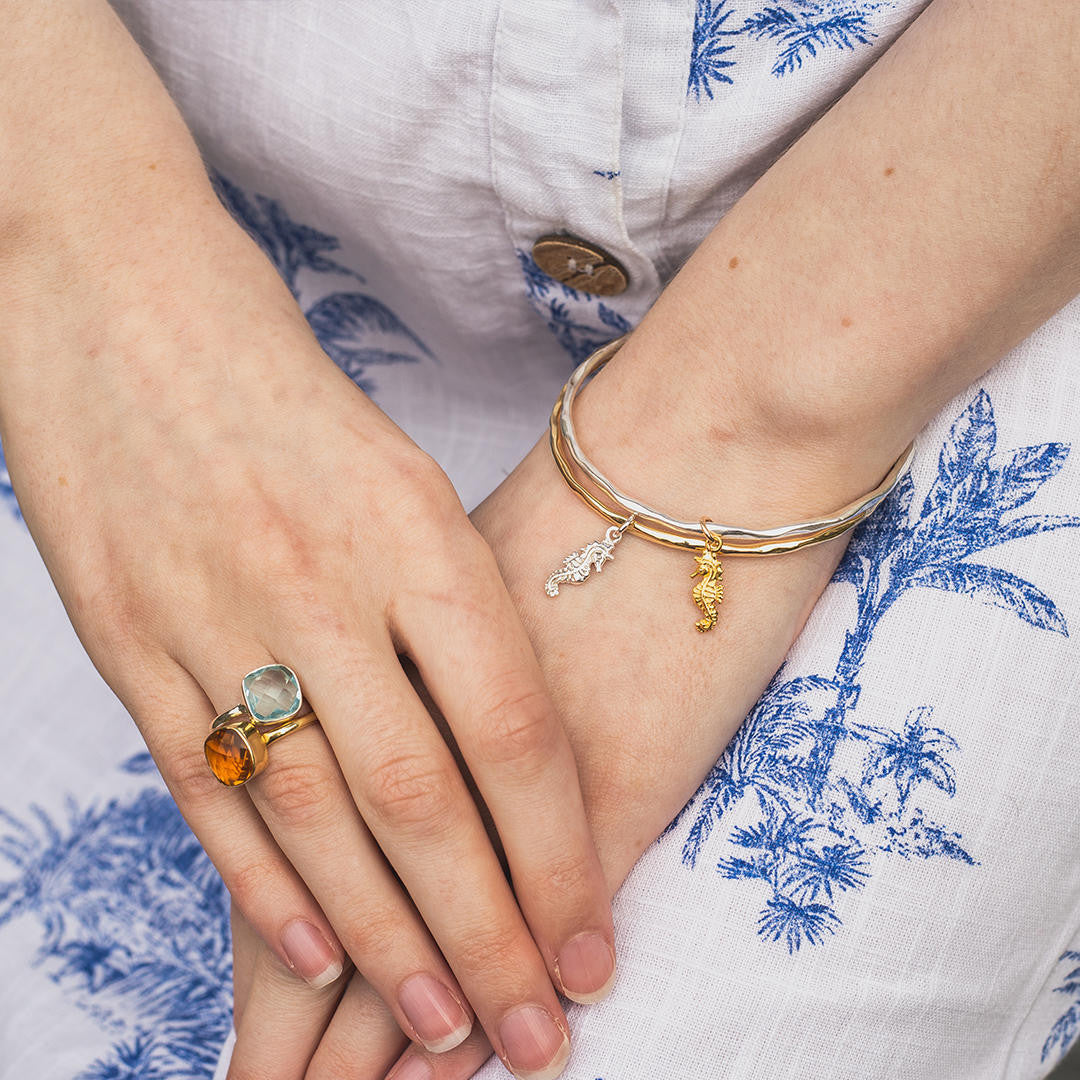 model wearing silver bangle with gold seahorse charm attached