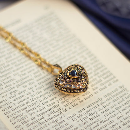 sapphire vintage hart locket in gold sitting on an opened book