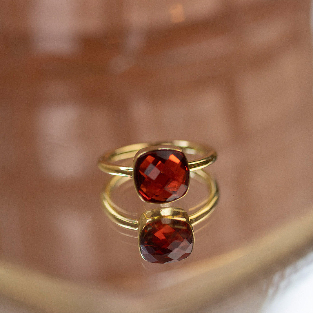 garnet cocktail ring in gold on a glass table